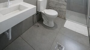 Un baño moderno con lavamanos, inodoro y ducha blancos.