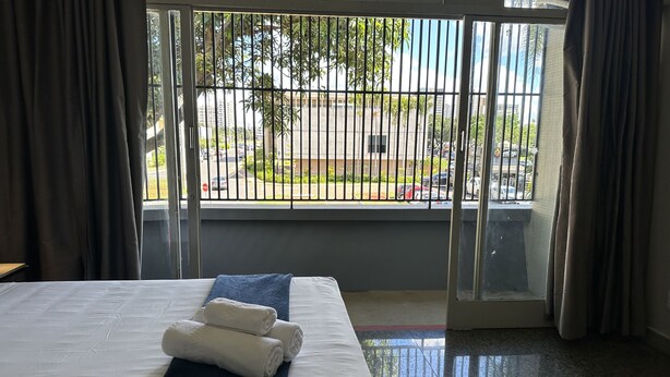 Una habitación de hotel con una cama, un ventanal con vista a la calle y cortinas.
