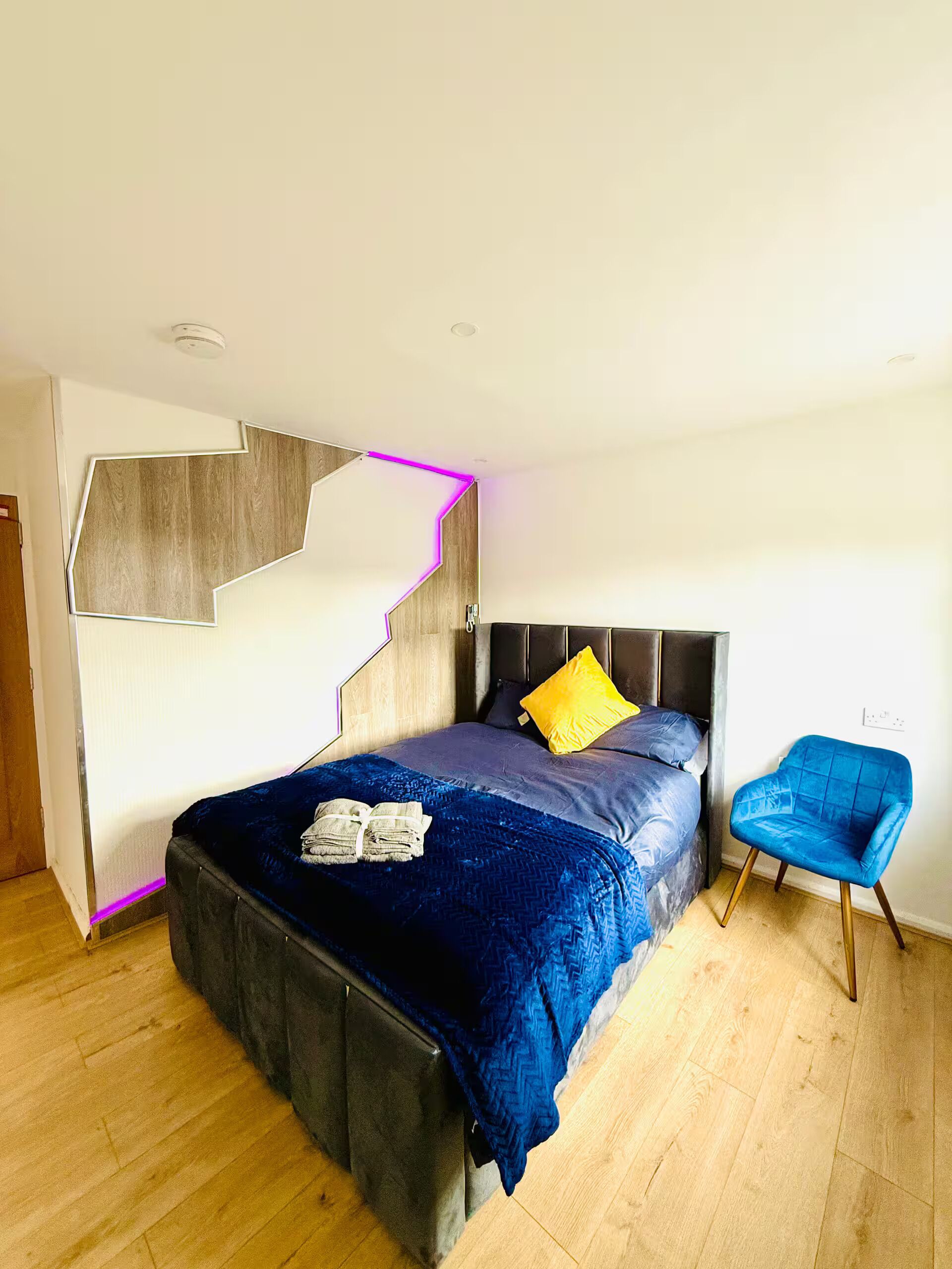 Ein modernes Schlafzimmer mit Bett, Sessel und einem außergewöhnlichen Wanddesign.