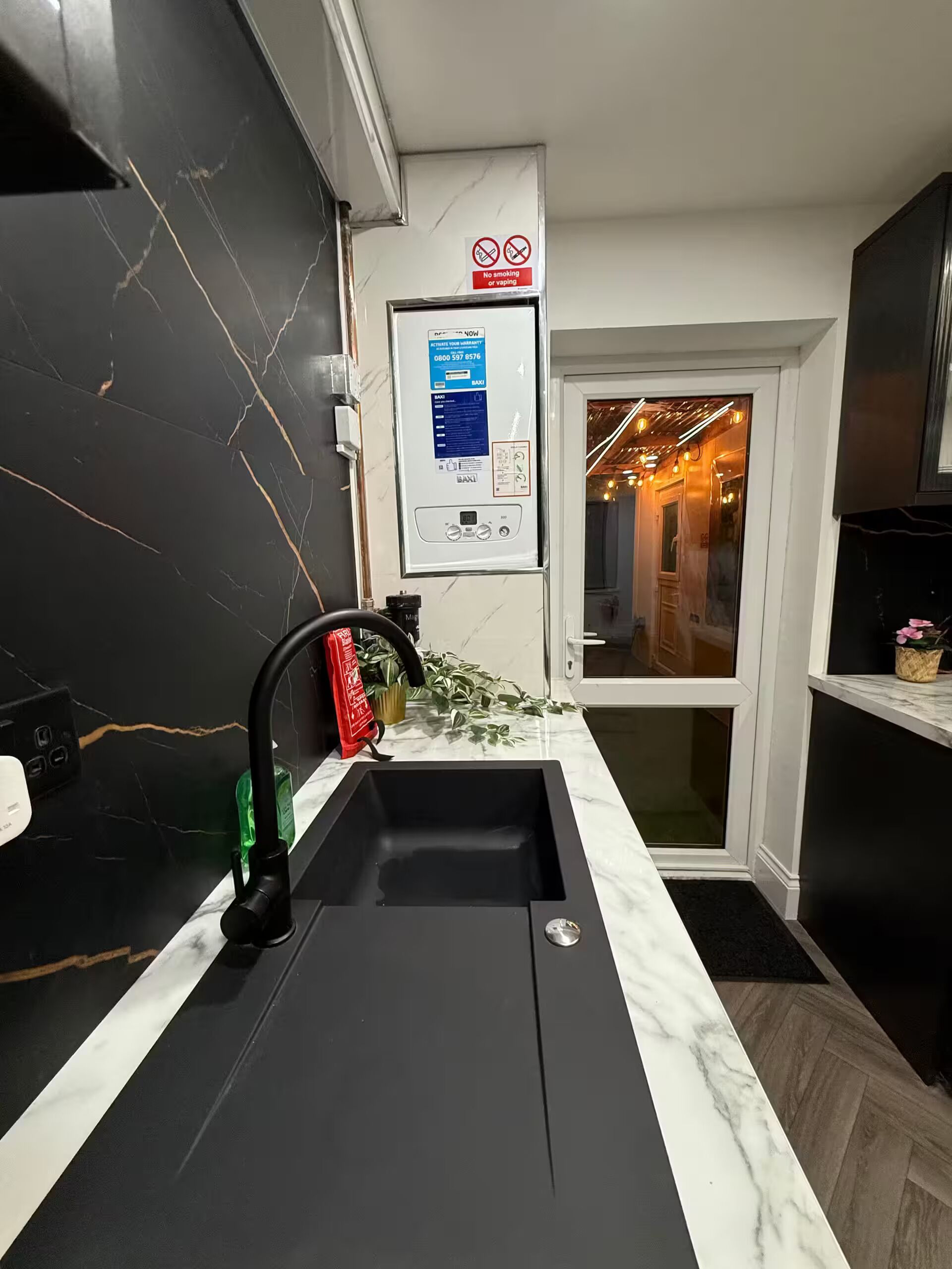 A modern kitchen with a black sink, marble countertop, and a no-smoking sign.