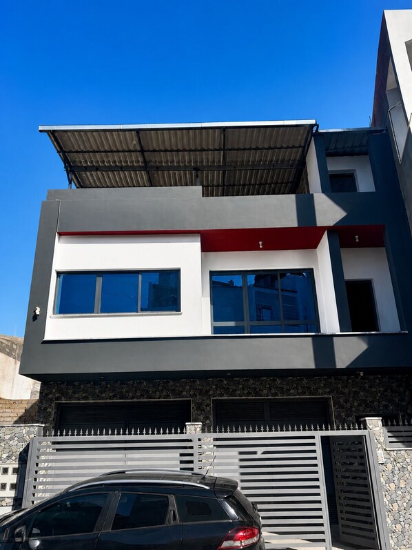 A modern two-story building with a flat roof, large windows, and a gated entrance.