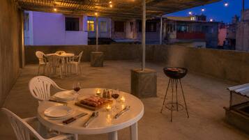 An outdoor dining area with tables, chairs, a grill, and candles.