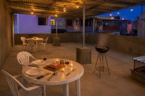 Un espacio de comedor al aire libre con mesas, sillas, una parrilla y velas.
