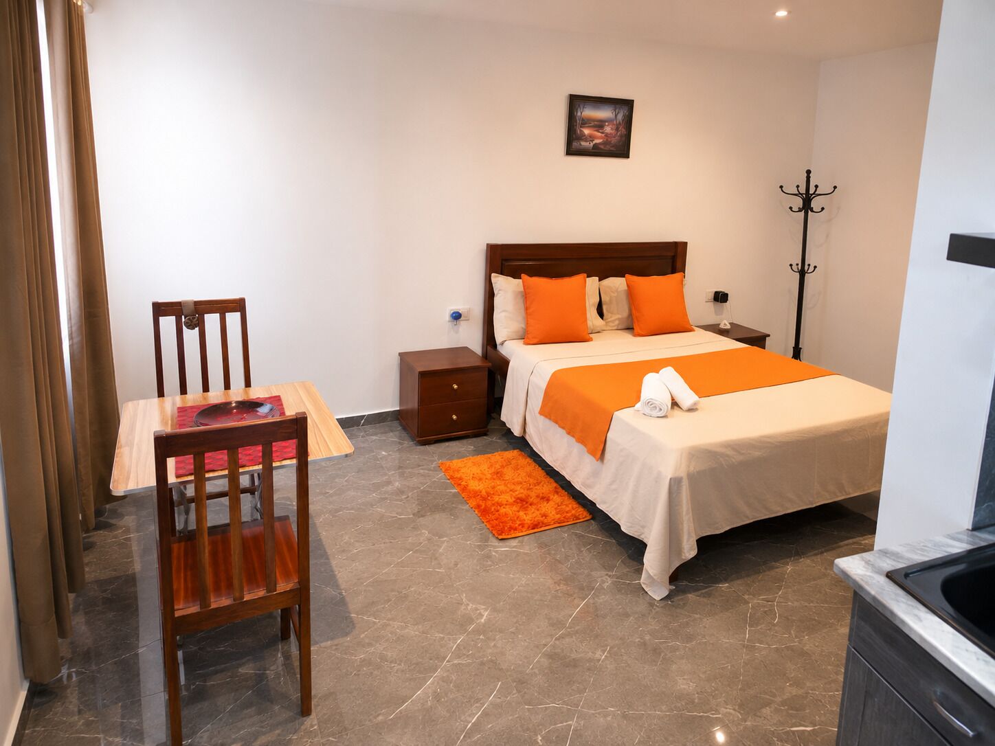 Ein Hotelzimmer mit Bett, Nachttisch, Stuhl und einem kleinen Tisch mit roter Unterlage.