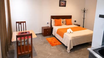 Ein Hotelzimmer mit Bett, Nachttisch, Stuhl und einem kleinen Tisch mit roter Unterlage.
