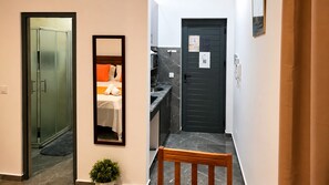 A hotel hallway with a bed, a mirror, a door, and a bench.