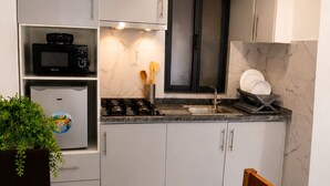 Una cocina moderna con gabinetes blancos, un microondas negro, una estufa a gas y un lavamanos.