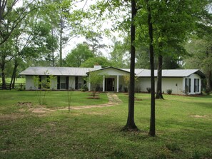 A two-story house with a front porch, a small garden, and a paved driveway.