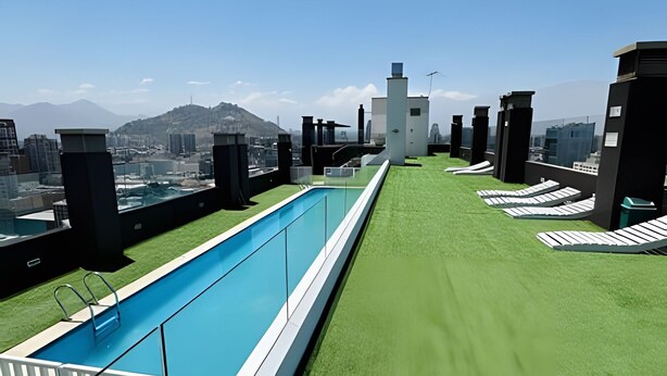 Una piscina en la azotea con vistas despejadas al paisaje urbano y montañas a lo lejos.