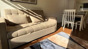 Una sala de estar con sofá, una mesa de centro y un comedor con sillas.