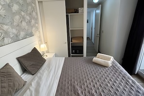 A hotel room with a bed, a nightstand, a lamp, a wardrobe, and a view of the hallway. - Spacious apt. 3 bedrooms. Fully equipped downtown Stgo (Santiago)