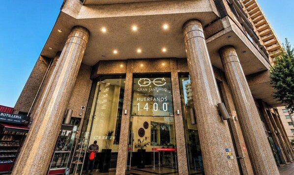 A building with large columns, a glass entrance, and a sign reading 'Gran Santiago Edificio Huertos 1400'. - Spacious apt. 2 bedr. Fully equipped downtown Stgo. (Santiago)