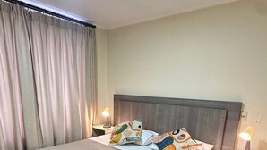 A hotel room with a large bed, two bedside tables, a headboard, and a window with curtains. - Spacious apt. 2 bedr. Fully equipped downtown Stgo. (Santiago)
