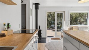 Een moderne keuken met een houten aanrecht, een ingebouwde oven en een groot raam met uitzicht op een terras.
