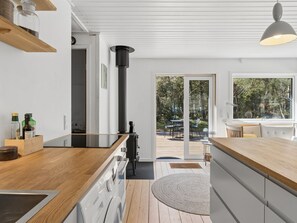 Eine moderne Küche mit Holzarbeitsplatte, einem Einbauofen und einem großen Fenster mit Blick auf eine Terrasse.