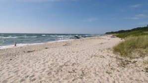 Een strand met zand, golven en een heldere lucht.