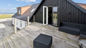 A modern building with a sloped roof, a wooden deck, and a large open doorway. - "Strandulf" - 1km from the sea by Interhome (Svaneke)