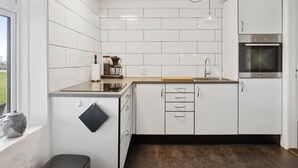 A modern kitchen with white cabinets, a built-in oven, and a coffee maker on the counter. - "Strandulf" - 1km from the sea by Interhome (Svaneke)