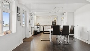 A modern kitchen with white cabinetry, a dining area with black chairs, and a view through a window. - "Strandulf" - 1km from the sea by Interhome (Svaneke)