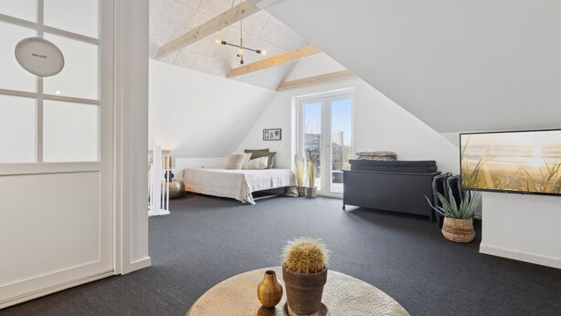 A modern loft bedroom with a large window, a bed, a sofa, and a TV. - "Strandulf" - 1km from the sea by Interhome (Svaneke)