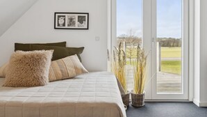 A bedroom with a bed, pillows, a framed picture, and a view through a door. - "Strandulf" - 1km from the sea by Interhome (Svaneke)