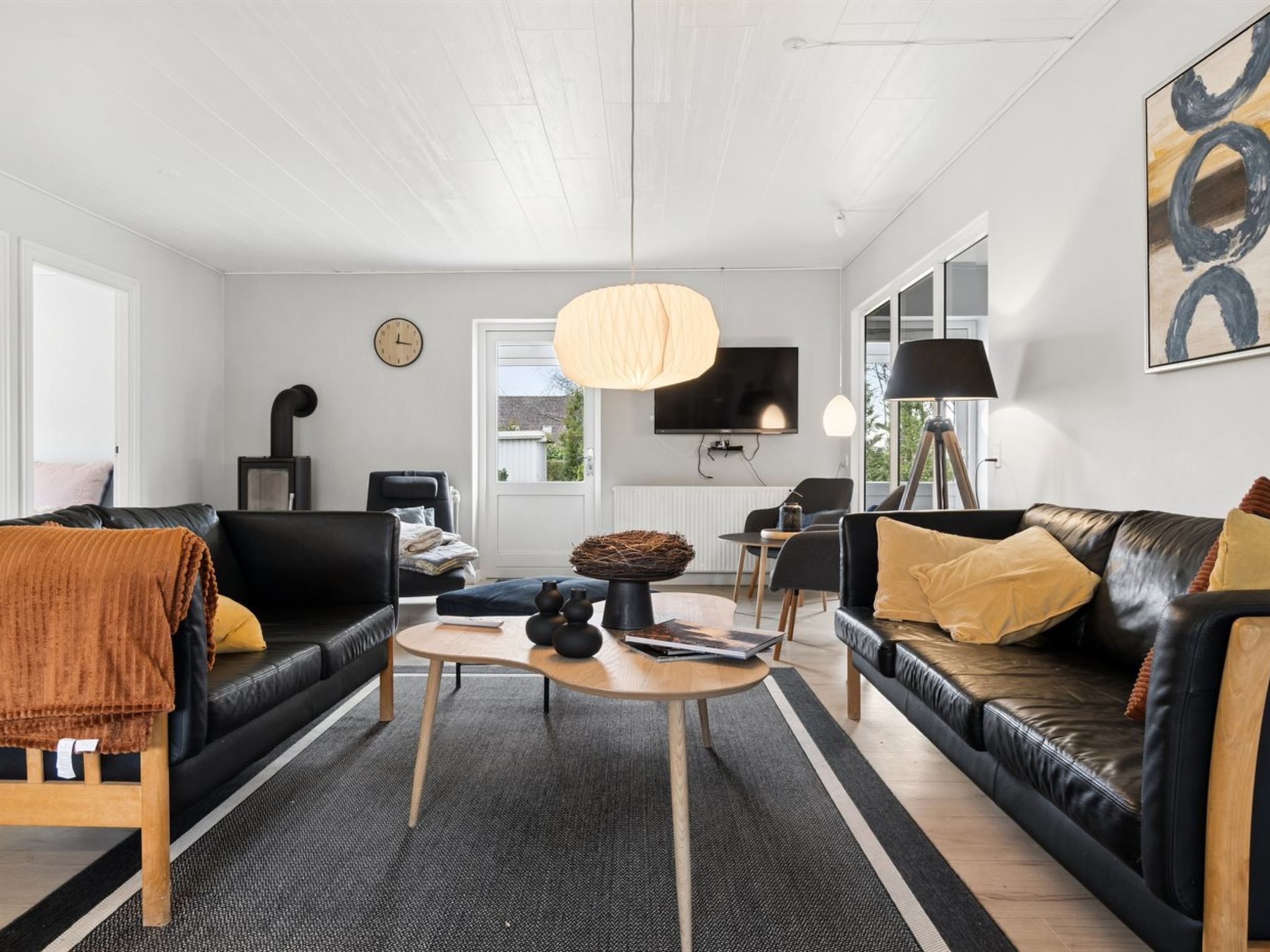 Ein modernes Wohnzimmer mit Kamin, Fernseher und großem Fenster.