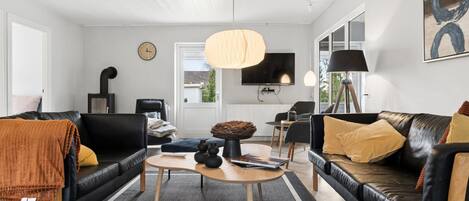 Ein modernes Wohnzimmer mit Kamin, Fernseher und großem Fenster.