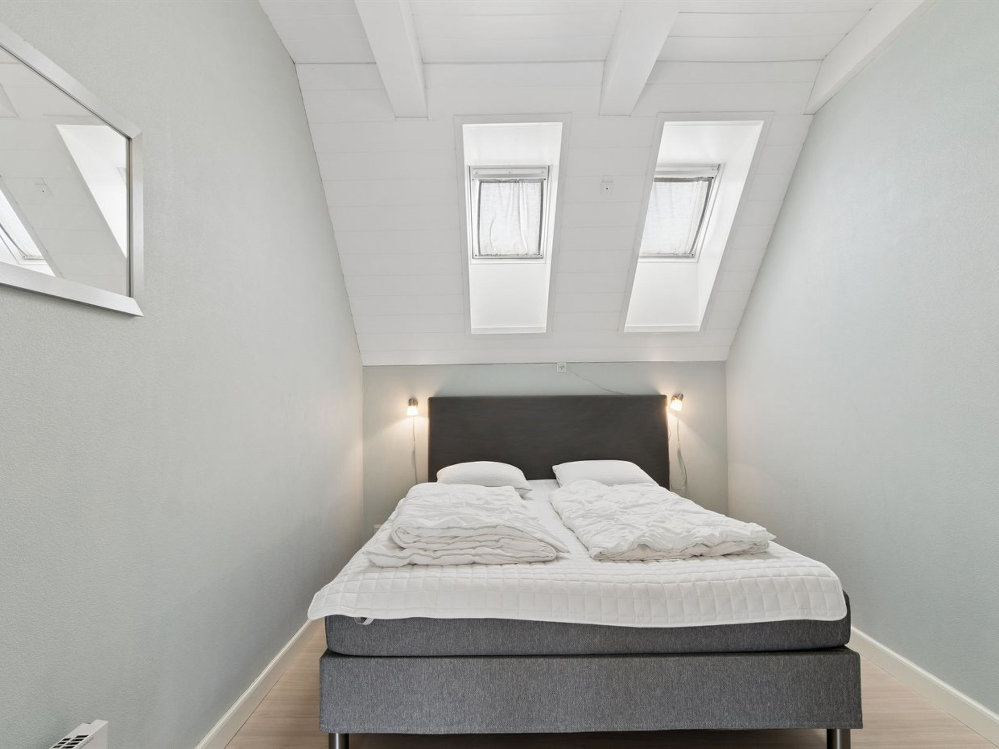 A bedroom with a bed, skylights, and a light fixture.