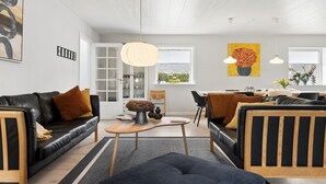 Ett modernt vardagsrum med en soffa, ett soffbord och en matplats med stolar.