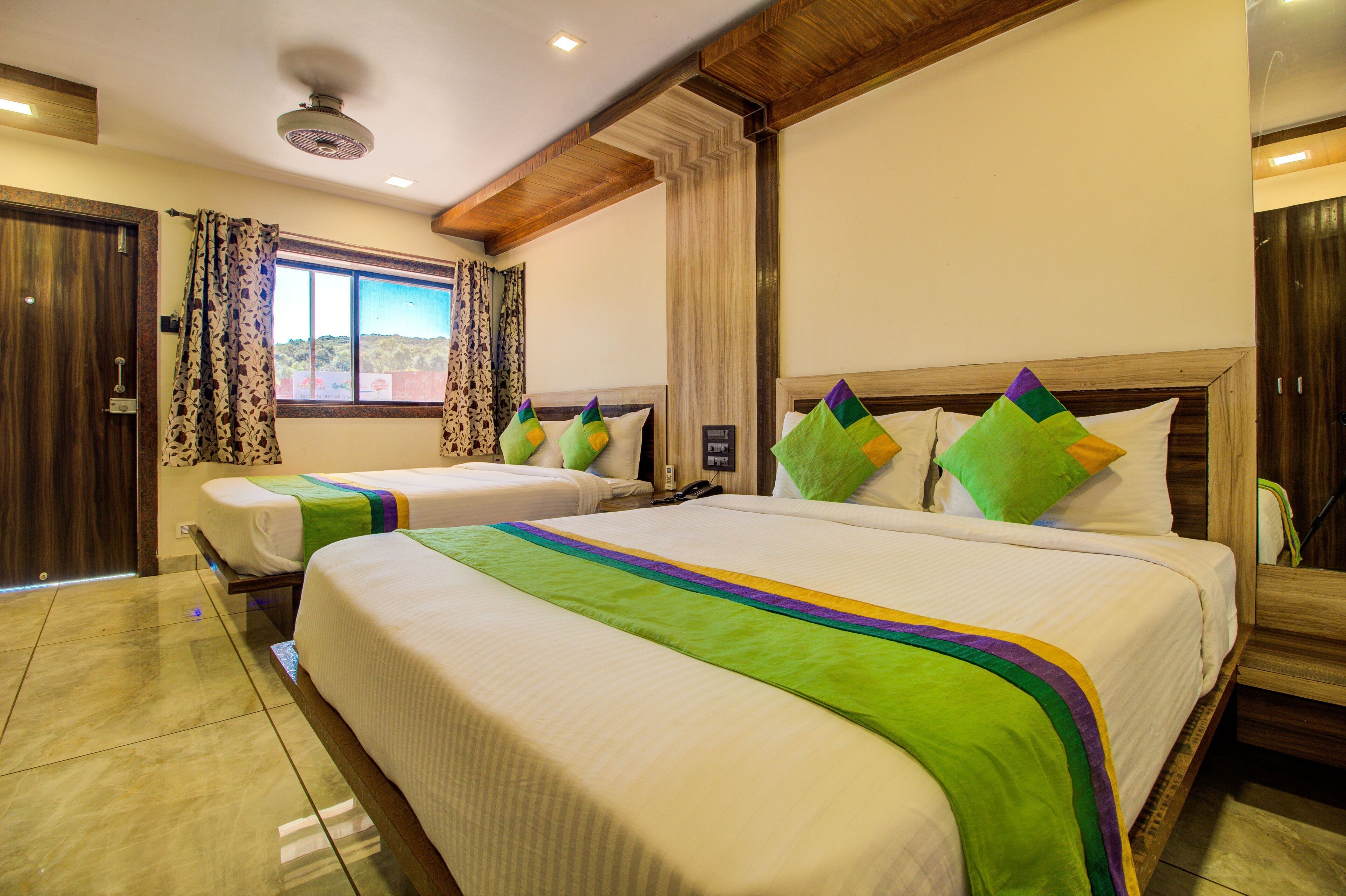 A hotel room with two beds, a large window, and a view of the outdoors.