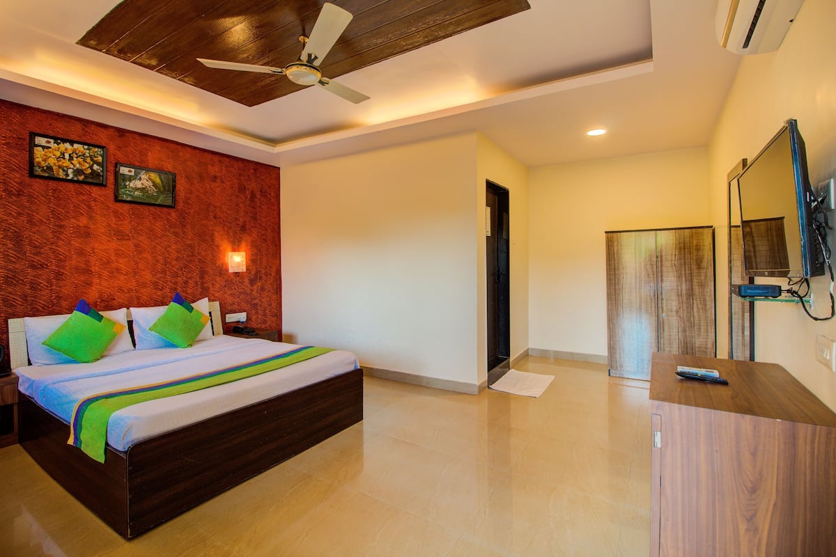 A bedroom with a bed, a ceiling fan, a TV, and a wooden cabinet.