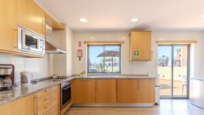 Una cocina moderna con armarios de madera, un microondas de acero inoxidable y un ventanal grande.