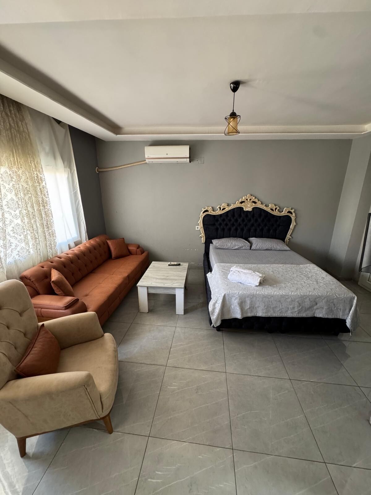 Een slaapkamer met een bed, een bank, een stoel en een kleine tafel.