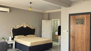 A bedroom with a bed, bedside table, chair, and a wooden door with a plaque.