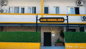 A multi-story hotel with balconies, air conditioning units, and a sign reading 'İLERİ KONAKLAMA'.