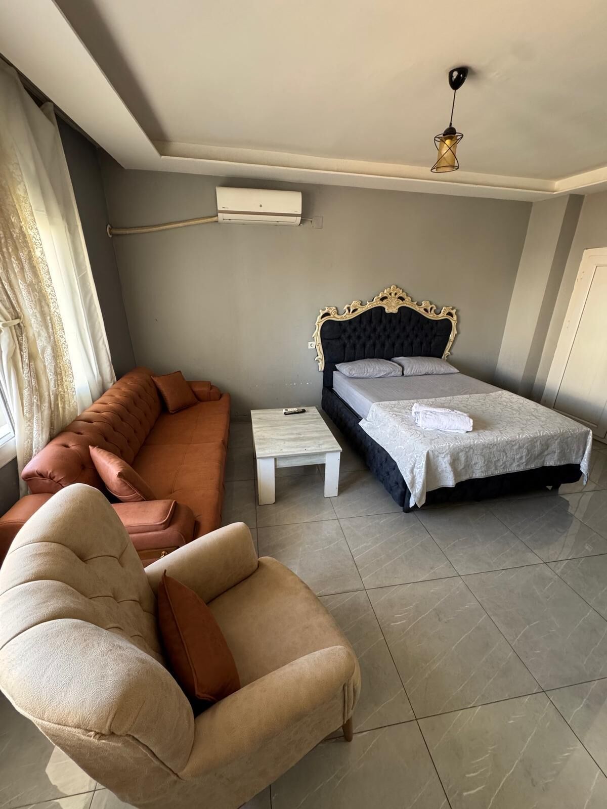 Een slaapkamer met een bed, een slaapbank, een stoel, een kleine tafel en een plafondlamp.