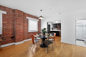 A dining area with a brick wall, a round table, and chairs.