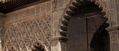 Una estructura arquitectónica ornamentada con intrincados grabados, varios arcos y un balcón con barandillas.