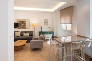 Ein modernes Wohnzimmer mit Sofa, Sessel, Couchtisch, Esstisch und Stühlen.