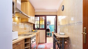 Une cuisine dotée de meubles en bois, d’un plan de travail, d’un évier et d’un coin repas avec une table et des chaises.