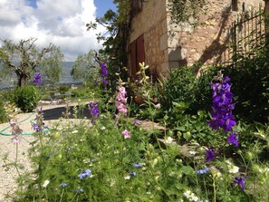 Un jardin agrémenté de diverses fleurs et plantes, un mur de pierre et une vue sur le paysage.