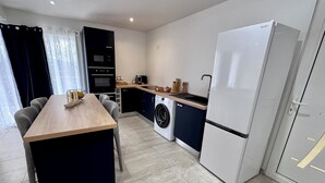 Una cocina compacta con lavadora, refrigerador y comedor con mesa y sillas.