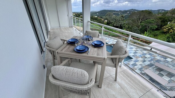 Un balcón con una mesa para dos, sillas y vistas al paisaje.