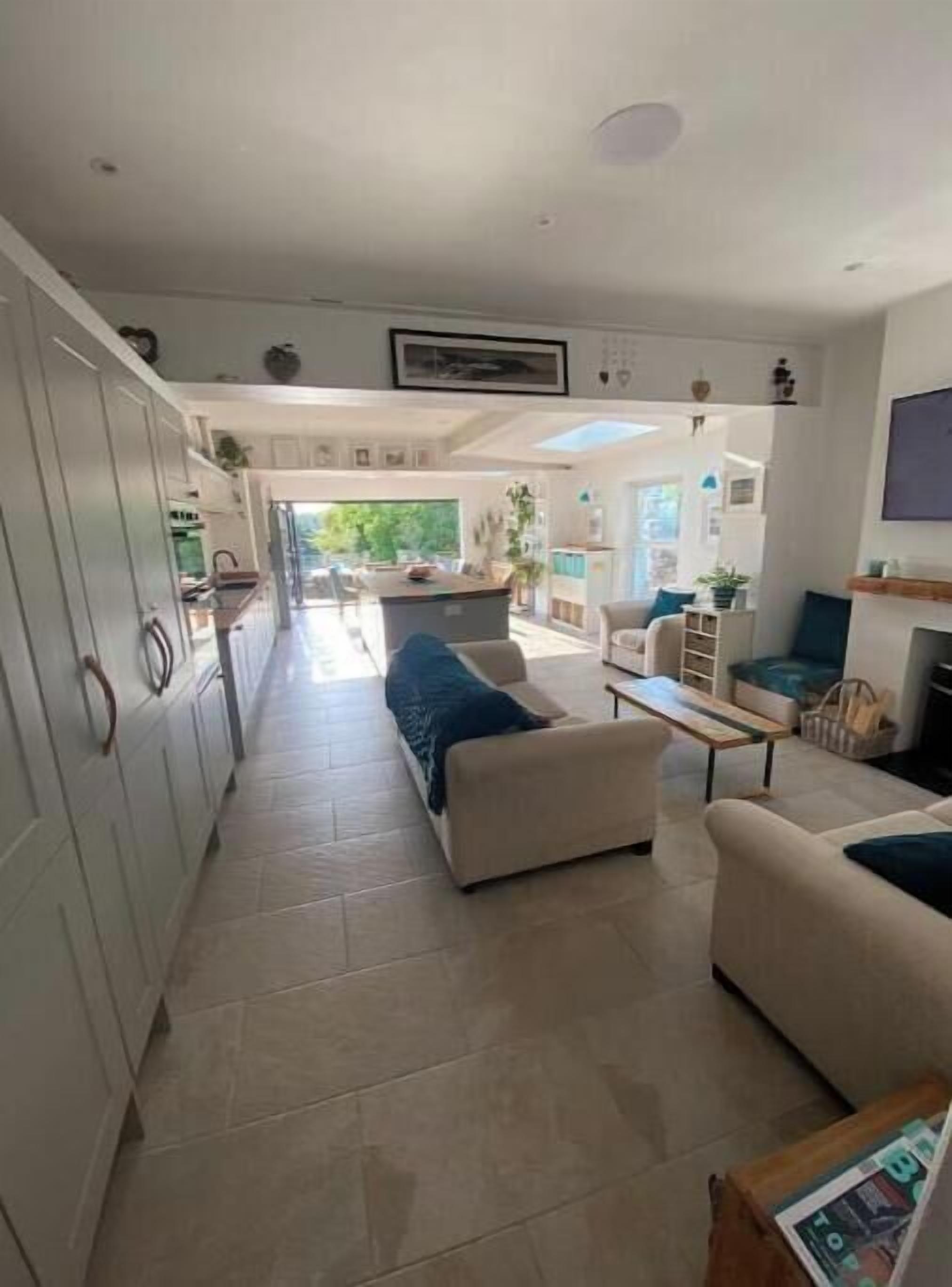 A spacious living area with a sofa, a coffee table, and a kitchen in the background.
