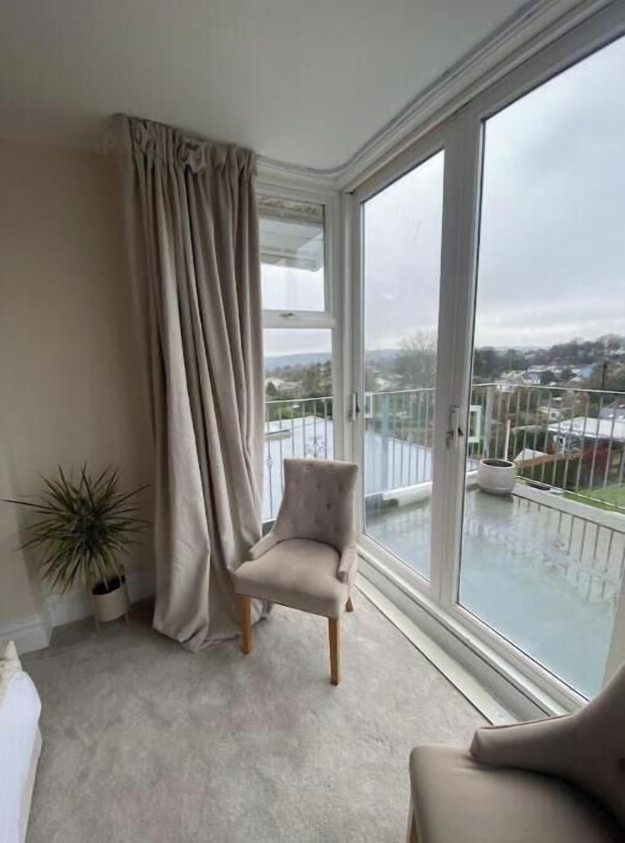 Ein Balkon mit Blick auf ein Wohngebiet, einem Sessel und einem Blumentopf.