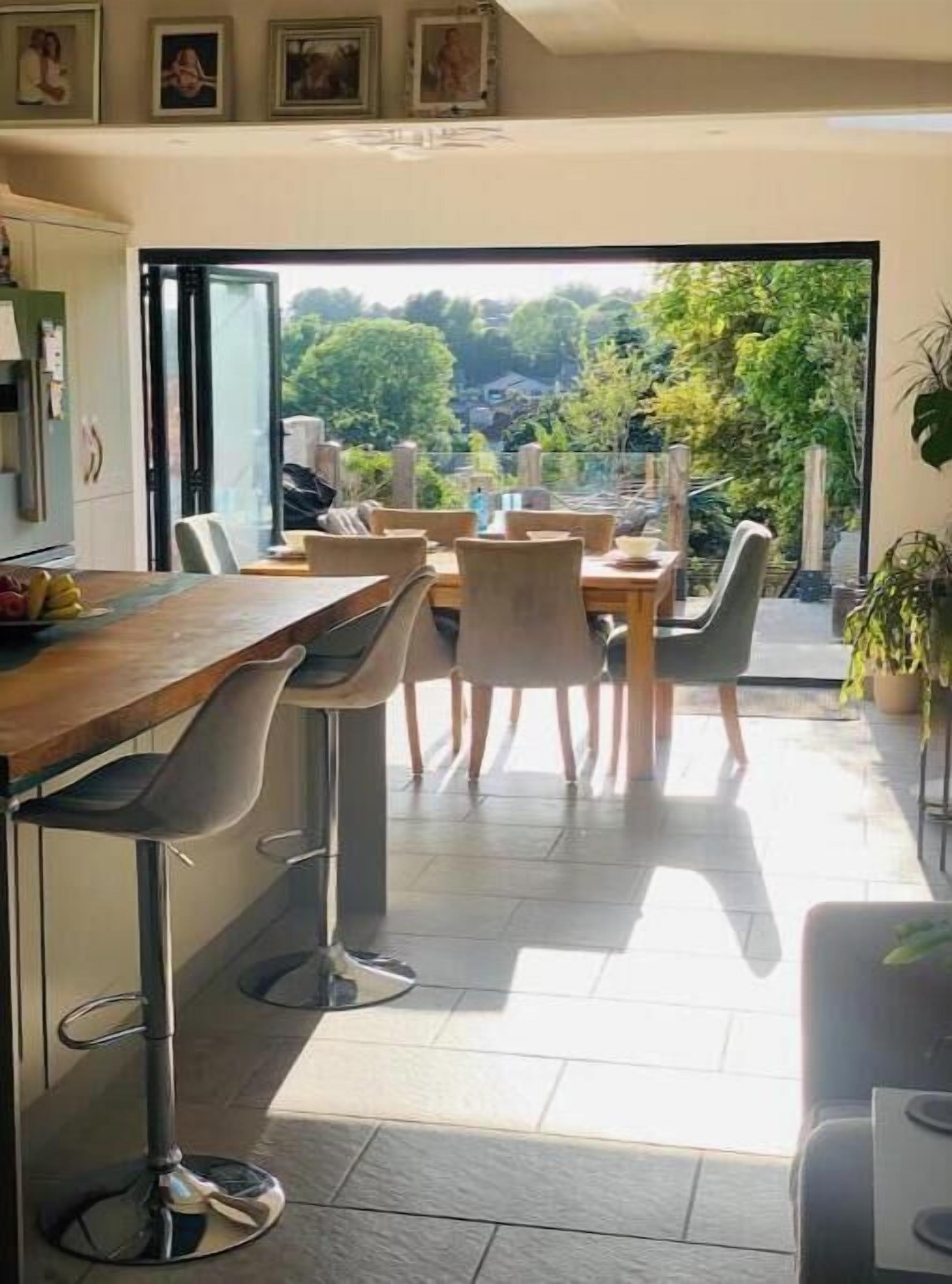 A dining area with a view of greenery, a bar area with stools, and a kitchen with cabinets.