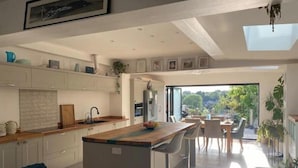 Una cocina moderna con una isla central, taburetes de bar y una zona de comedor con vistas al exterior.