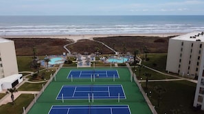 Een tennisbaan, een zwembad en uitzicht op het strand.