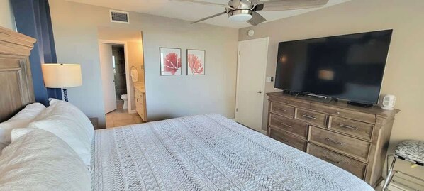 A bedroom with a large bed, a dresser, a television, and a ceiling fan. - On Beach Incredible Views - Remodel (South Padre Island)