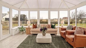 Ein Wintergarten mit einer Couch, einem Ledersessel und einem Couchtisch.